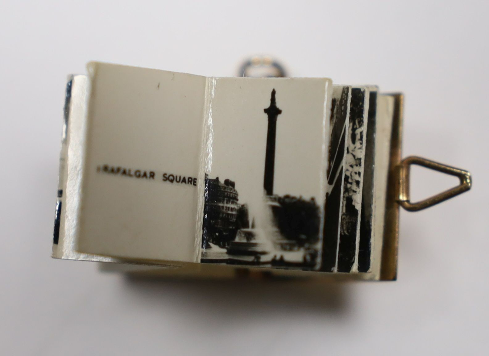 An enamelled 9ct gold photograph album charms with views and crest of London, 1.5cm gross 3.1 grams